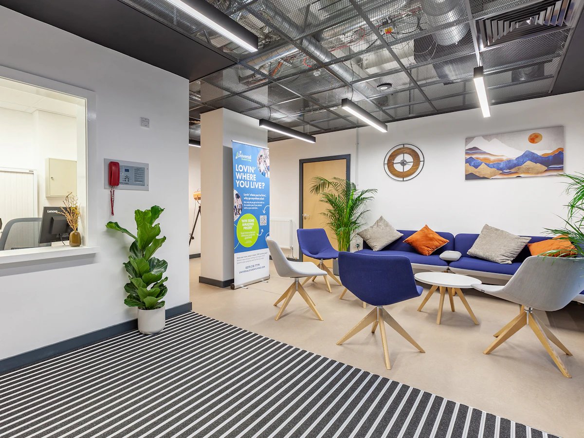 Blue sofa orange pillows modern chairs communal area at Fulham Palace Studios in London Student Accommodation