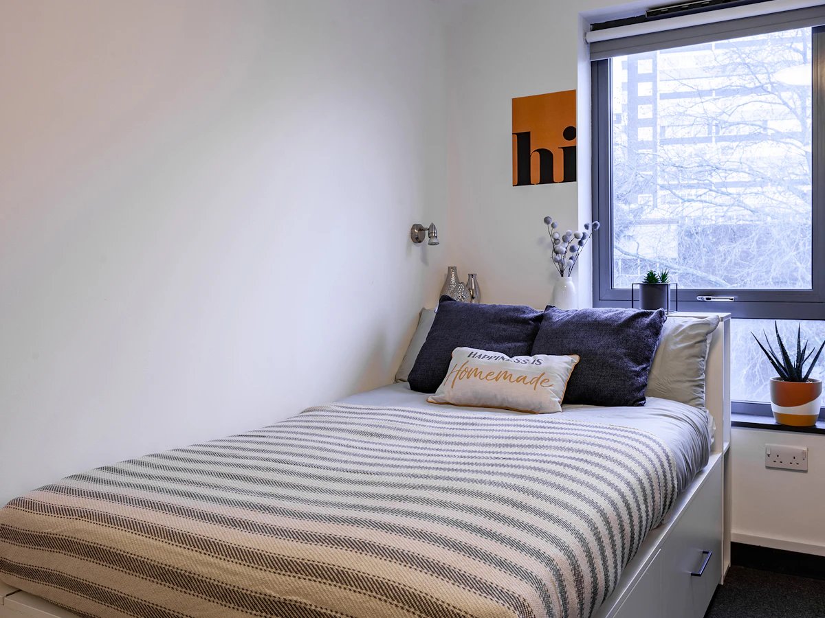 Bed with pillows blanket art window bedroom at Fulham Palace Studios in London Student Accommodation
