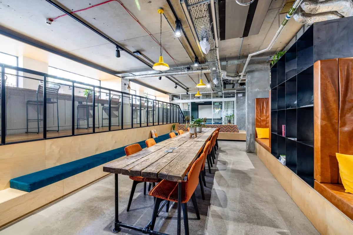 Long wooden table orange chairs communal area at Chapter Portobello in London Student Accommodation