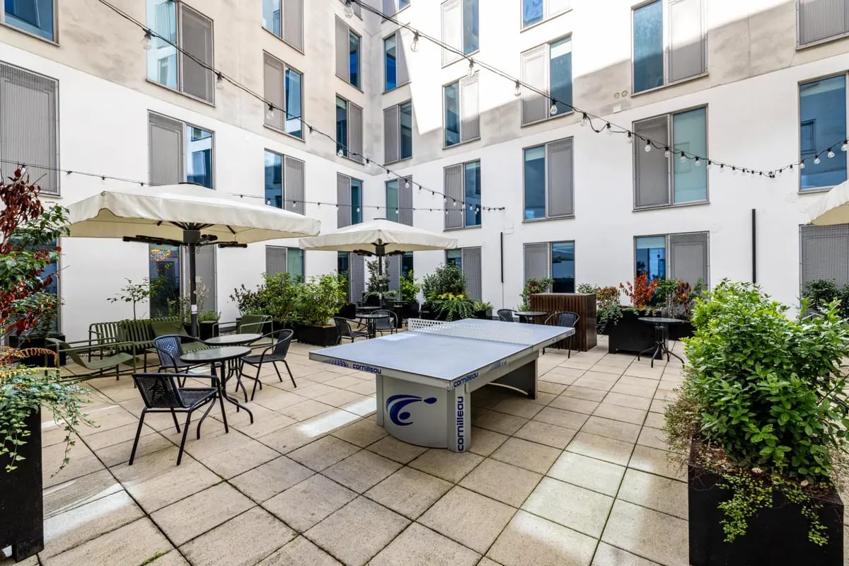 Ping pong table outdoor seating and umbrellas courtyard at Chapter Portobello in London Student Accommodation