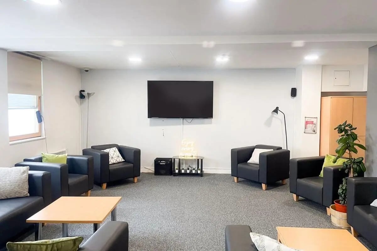 Modern lounge area with black sofas chairs and television living room at Don Gratton House in London Student Accommodation