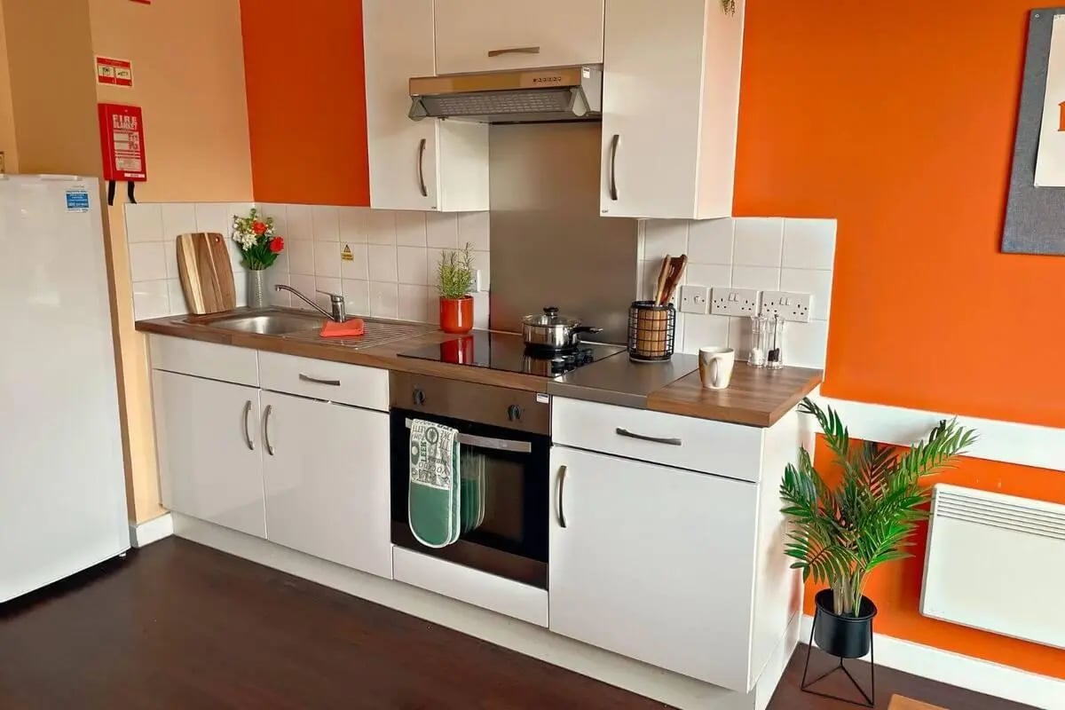 White cabinets sink stovetop oven and fridge kitchen at Don Gratton House in London Student Accommodation
