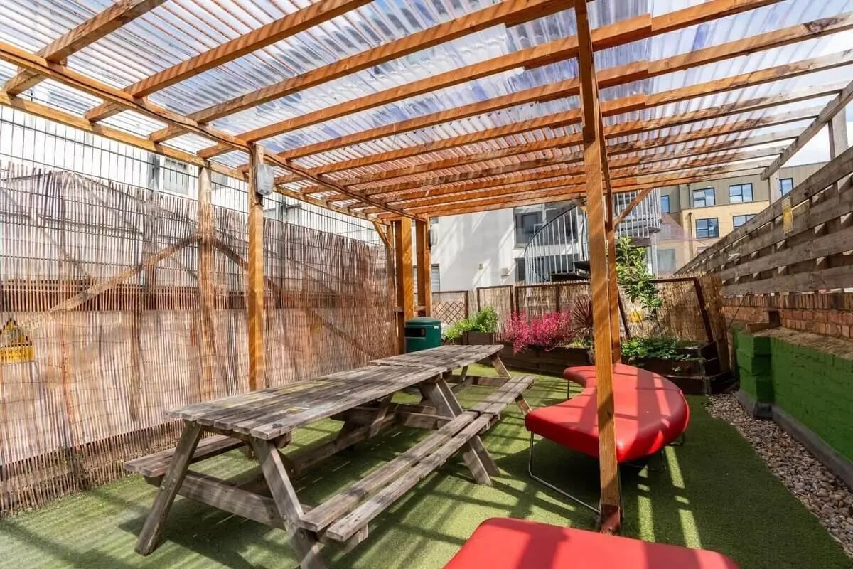 Wooden picnic table red seating area outdoor living space at Don Gratton House in London Student Accommodation