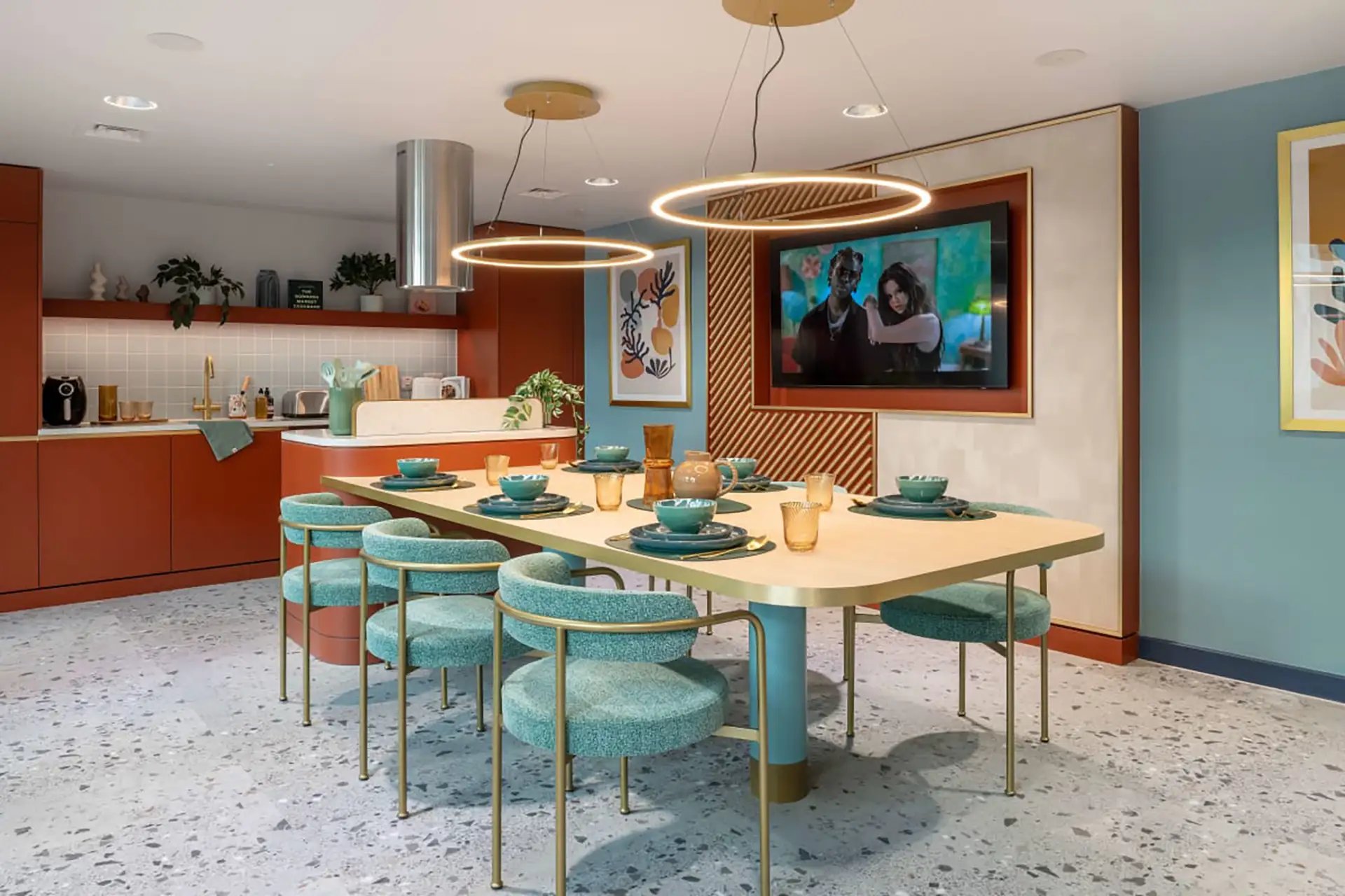 Dining table with teal chairs and kitchen area communal space at Wick Park in London Student Accommodation