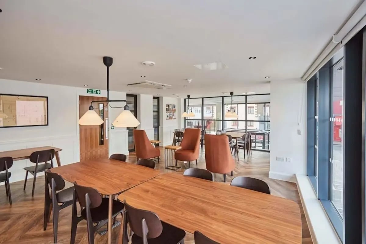 Wooden tables chairs and orange armchairs living room at Mannequin House in London Student Accommodation