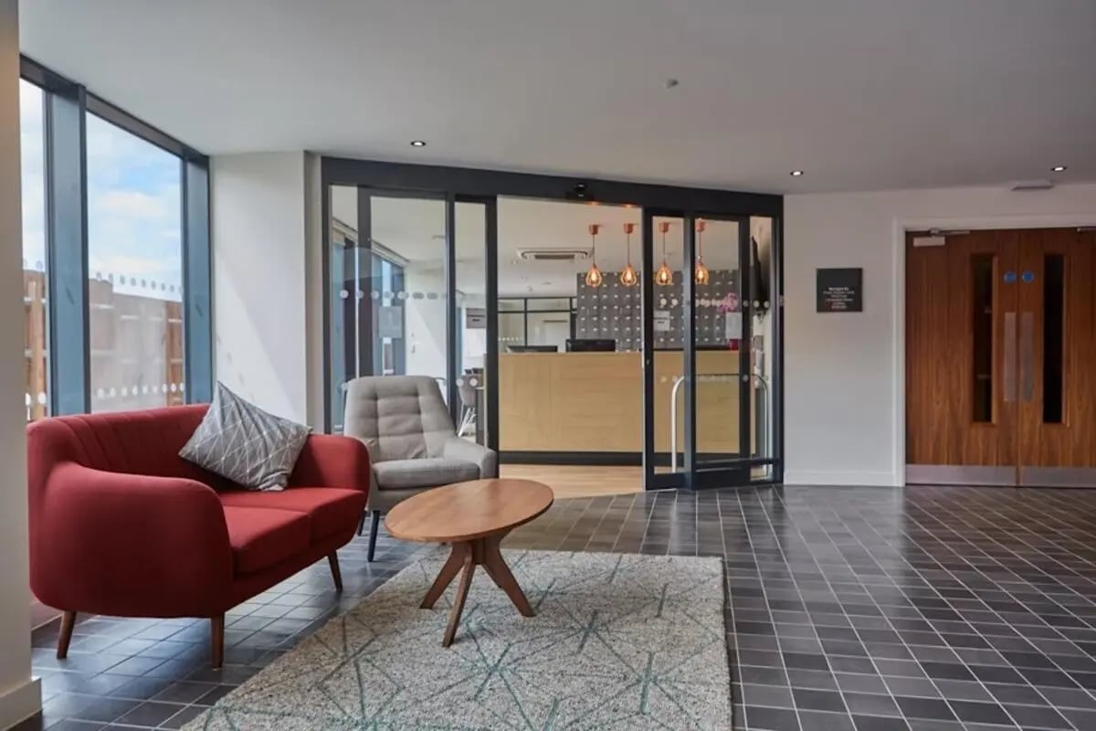 Red sofa grey armchair coffee table common area at Mannequin House in London Student Accommodation