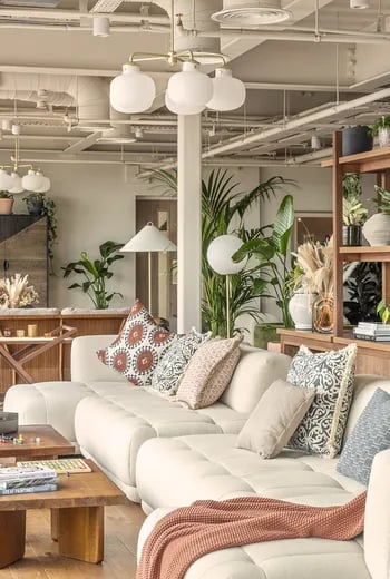 White sectional sofa patterned pillows plants living area at ARK Wembley in London Student Accommodation