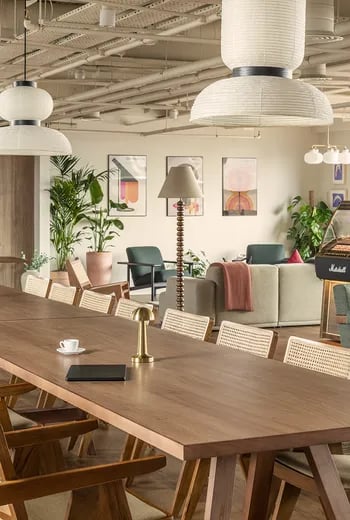 Large wooden table with chairs art plants and sofas living room at ARK Wembley in London Student Accommodation
