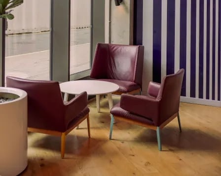 Three burgundy chairs and white table lounge area at Scape Wembley in London Student Accommodation