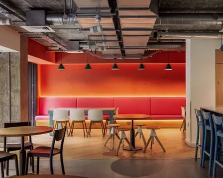 Modern seating with orange wall and bar stools communal area at Scape Wembley in London Student Accommodation