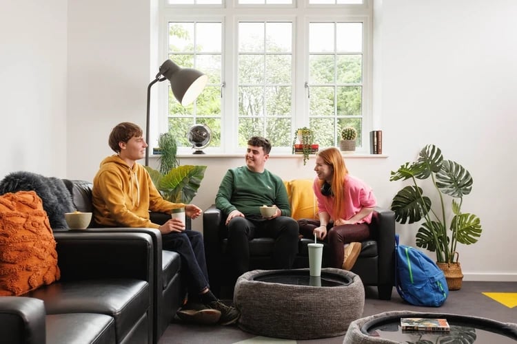 Students relaxing on couches with snacks and drinks Living room at Houghall Court in Durham Student Accommodation