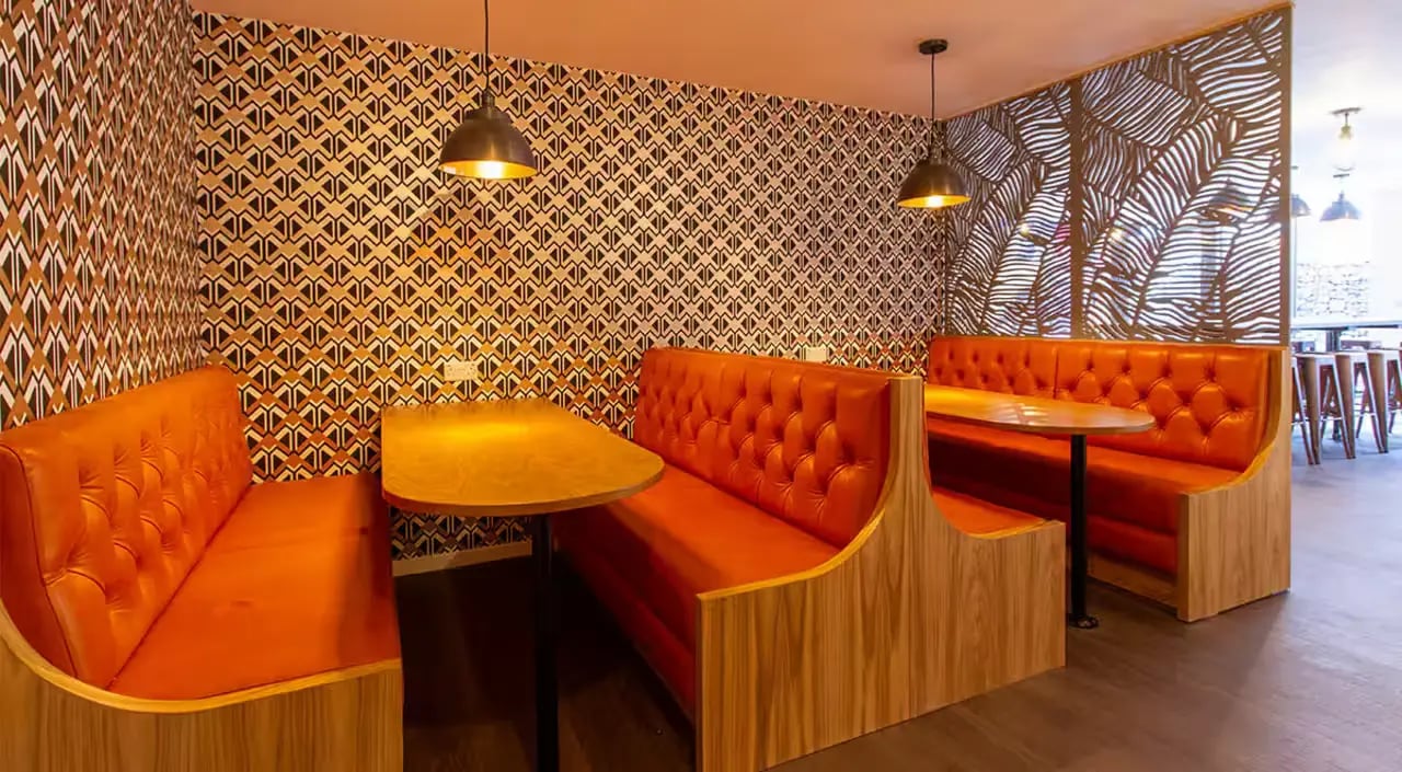 Orange booths tables patterned wallpaper dining area at Dean Street Works in Bristol Student Accommodation