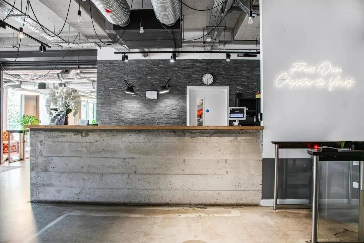 Concrete reception desk with signage and turnstiles reception at Chapter Lewisham in London Student Accommodation