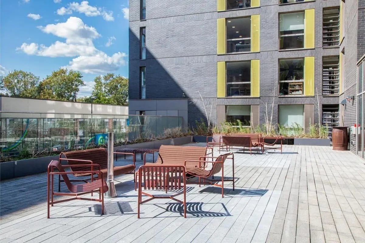 Metal benches and chairs on a paved patio exterior at Chapter Lewisham in London Student Accommodation