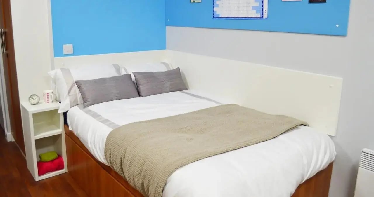 Bed nightstand clock and towels bedroom at Kaplan Living Nottingham in Nottingham Student Accommodation