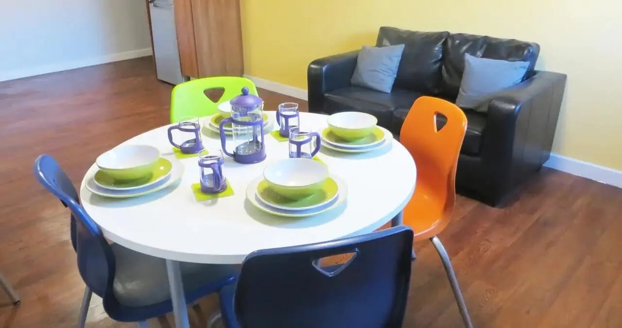 Table with place settings and couch living room at Kaplan Living Nottingham in Nottingham Student Accommodation
