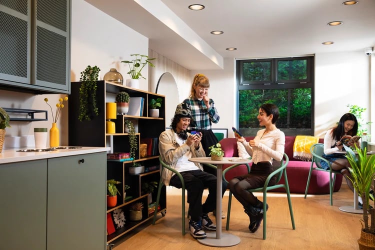 Students socialising in lounge area with kitchen elements at Student Living Heights in London Student Accommodation