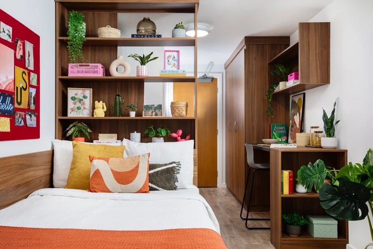 Bed pillows shelves desk and plants bedroom at Student Living Heights in London Student Accommodation