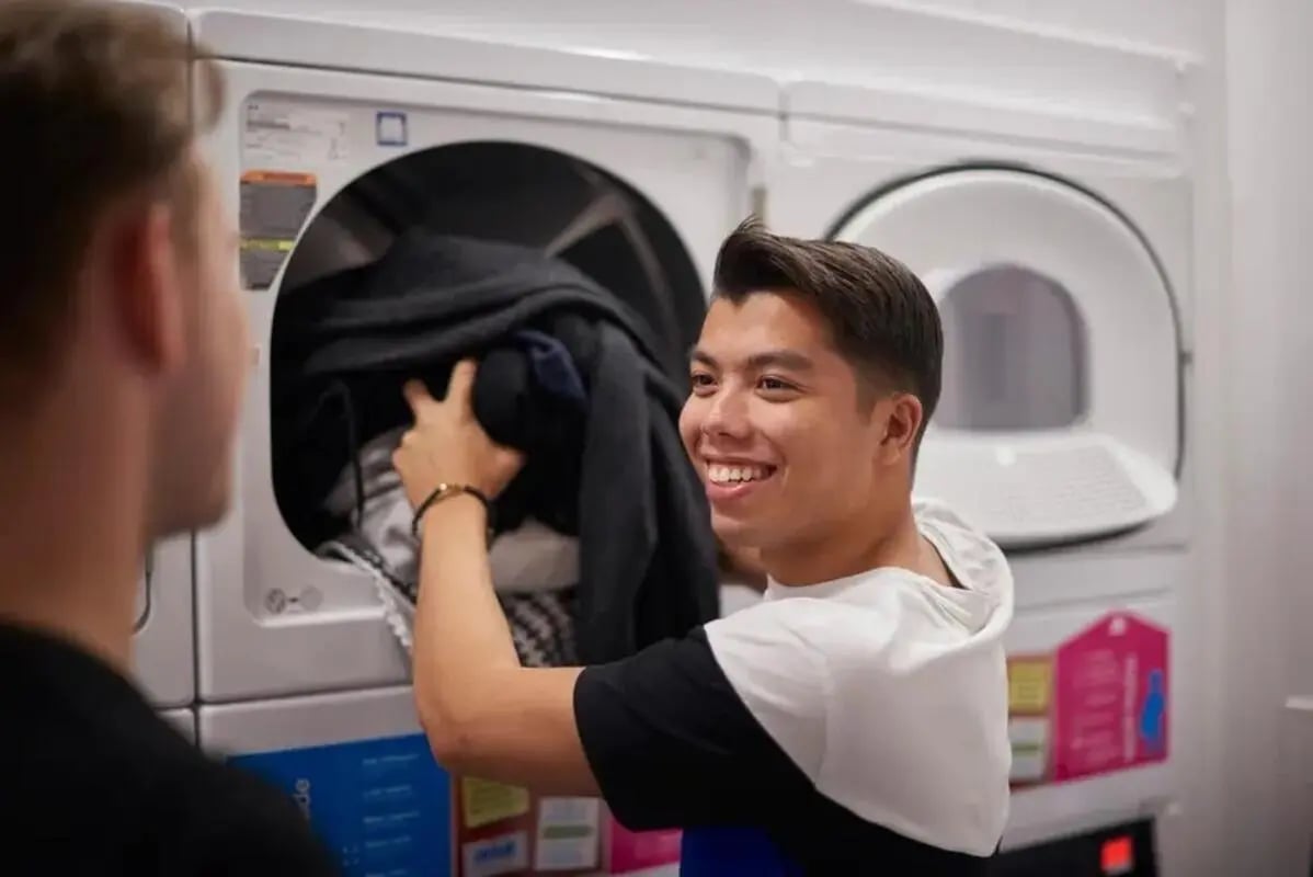 Two students loading clothes into washing machines laundry room at Chapter Highbury in London Student Accommodation