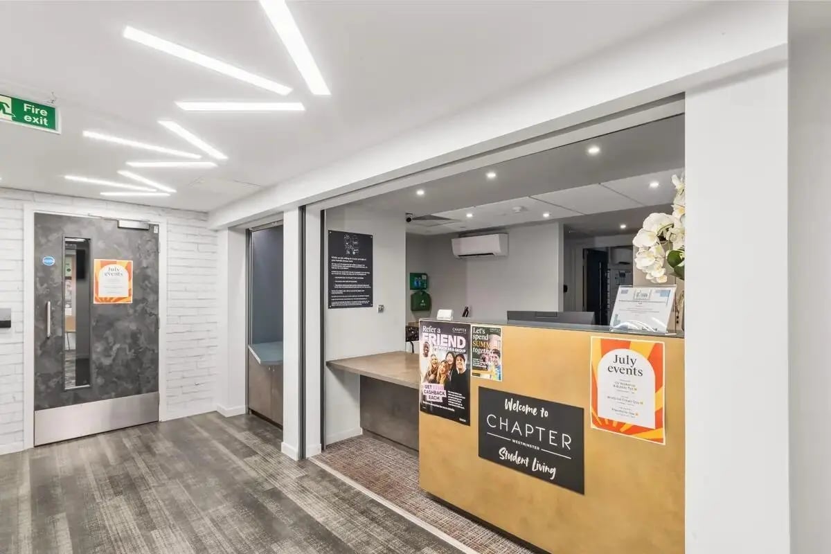 Reception desk with welcome sign and door exterior at Chapter Westminster in London Student Accommodation