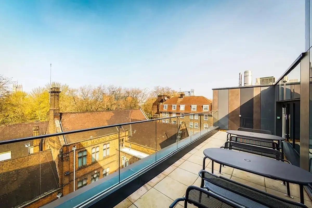 Outdoor seating with tables and benches exterior at Chapter Westminster in London Student Accommodation