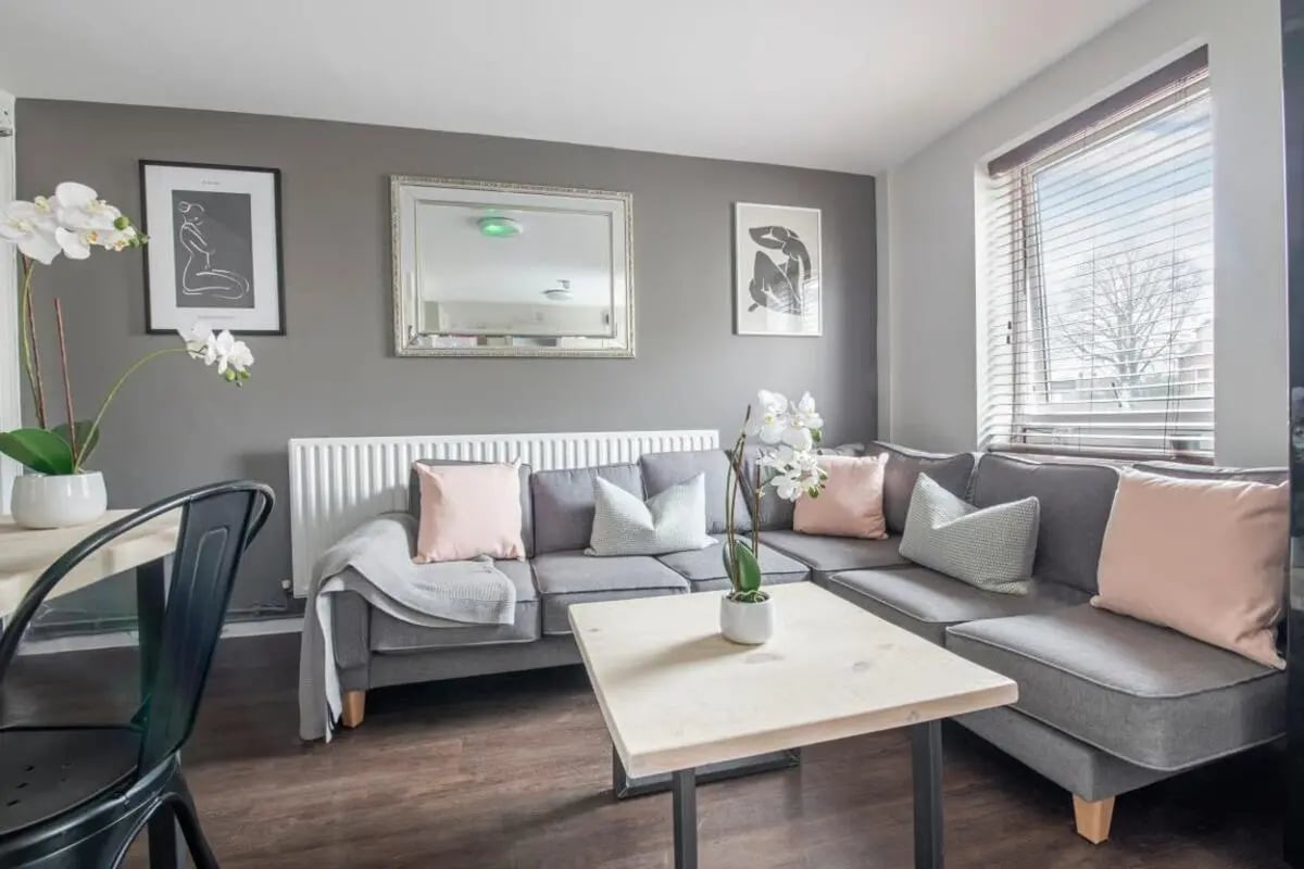 Grey sofa with pink and grey pillows living room at 4 Rob Roy House in Nottingham Student Accommodation