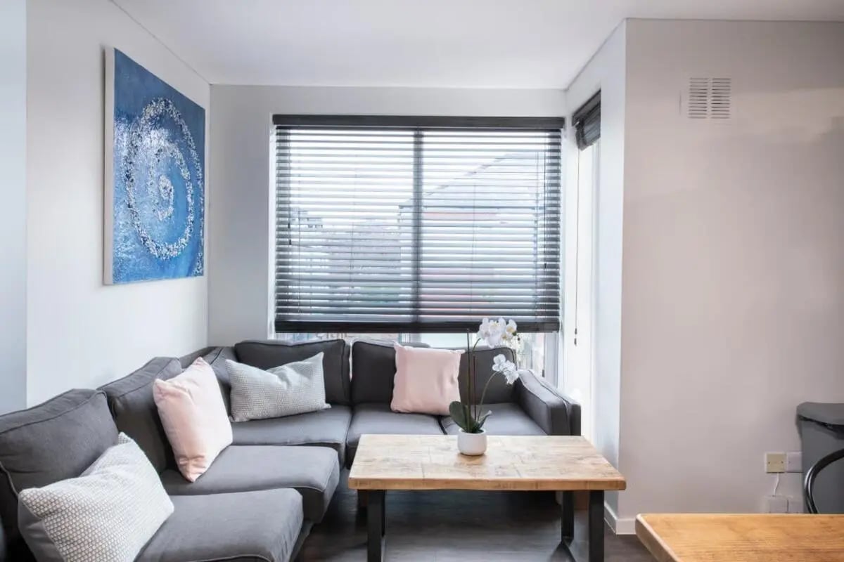 Grey sectional sofa with pink pillows and coffee table living room at 28 Church Street in Nottingham Student Accommodation