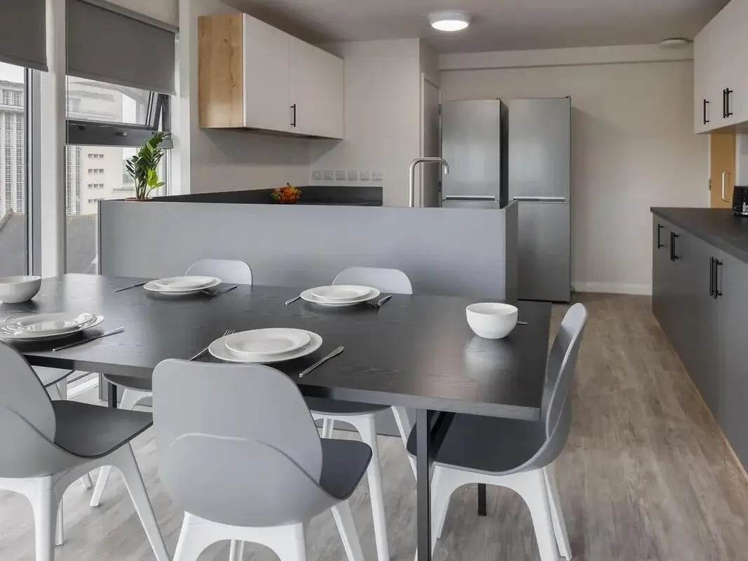 Dining table with place settings and kitchen area kitchen at Yugo Goldsmith Court in Nottingham Student Accommodation