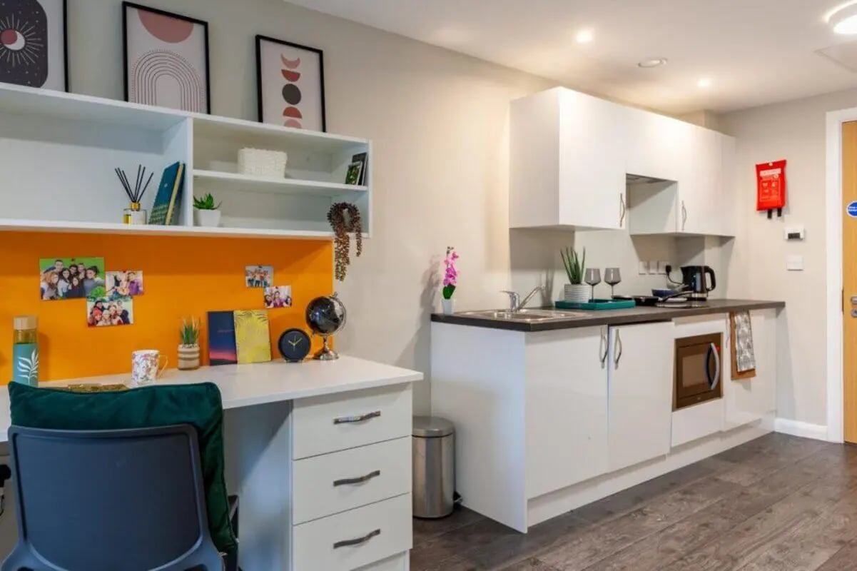 Desk with photos and small kitchen area living room at One Islington Plaza in Liverpool Student Accommodation