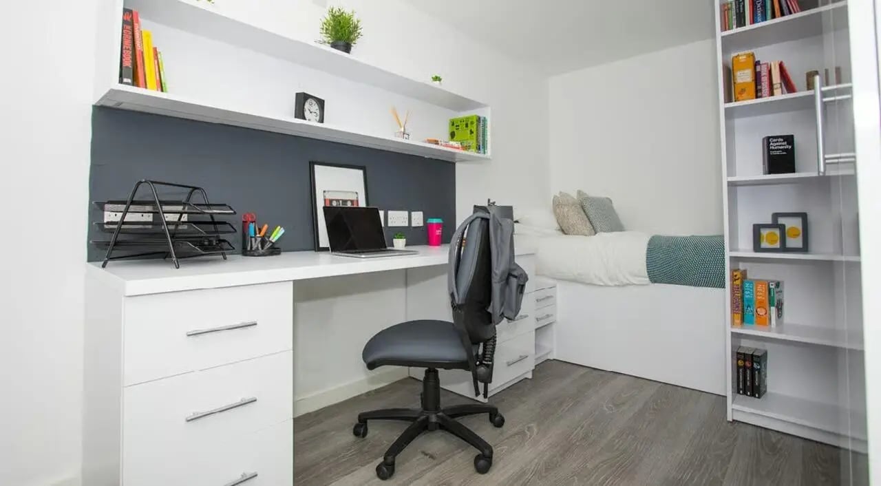 Desk with laptop chair bed and bookshelf student room at The Cube Ealing in London Student Accommodation