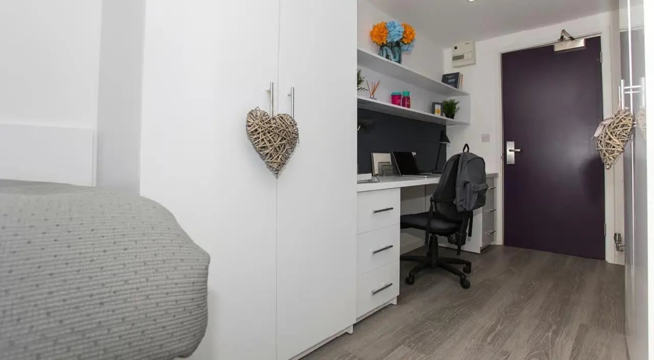 Wardrobe desk chair backpack and flowers study area at The Cube Ealing in London Student Accommodation