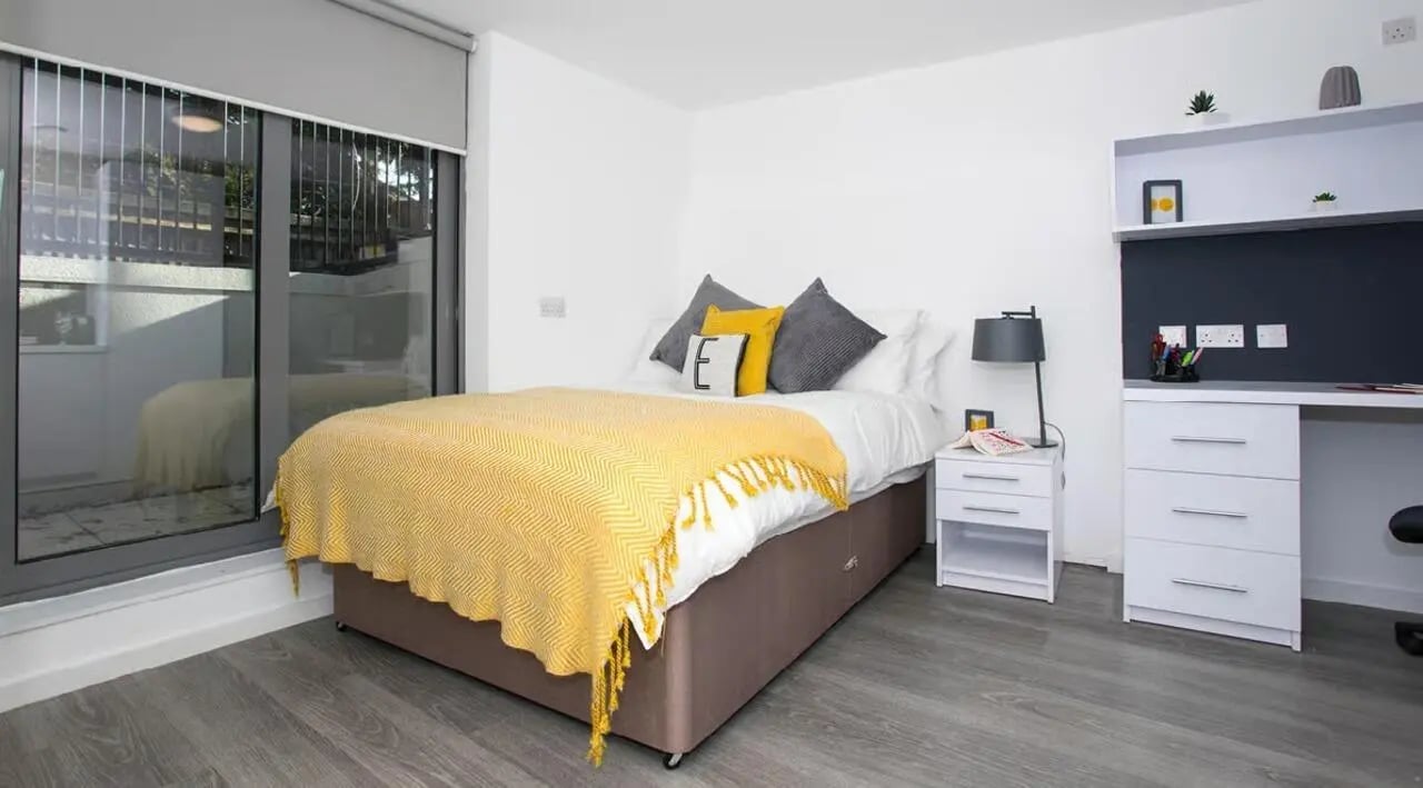 Bed with yellow blanket and desk area Bedroom at The Cube Ealing in London Student Accommodation