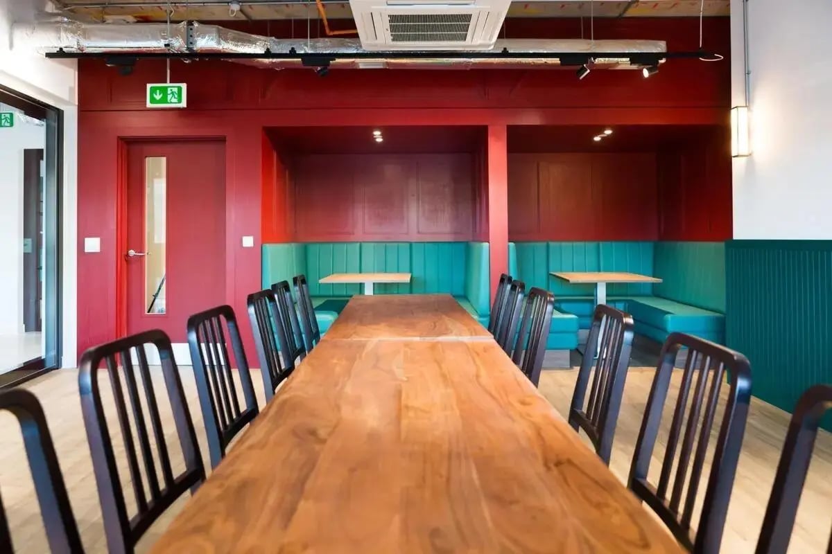 Wooden table with chairs in booths communal area at Chapter Highbury II in London Student Accommodation