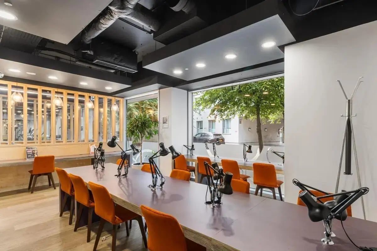 Long table with orange chairs desk lamps study area at Chapter South Bank in London Student Accommodation
