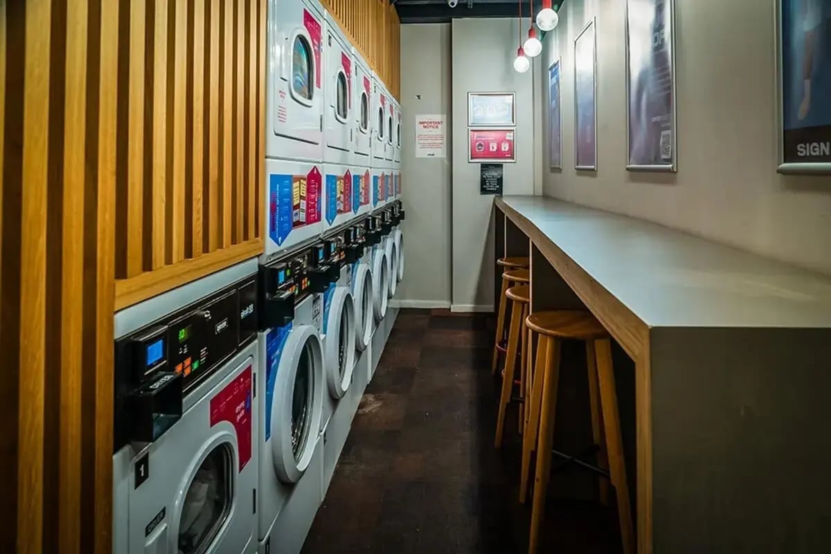 Washing machines and counter seating communal laundry area at Chapter South Bank in London Student Accommodation