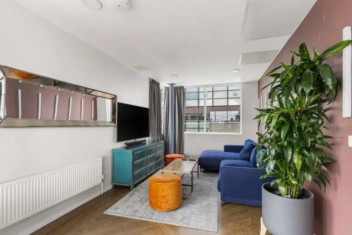 Blue couch mirrored art blue dresser orange ottoman living room at Chapter South Bank in London Student Accommodation