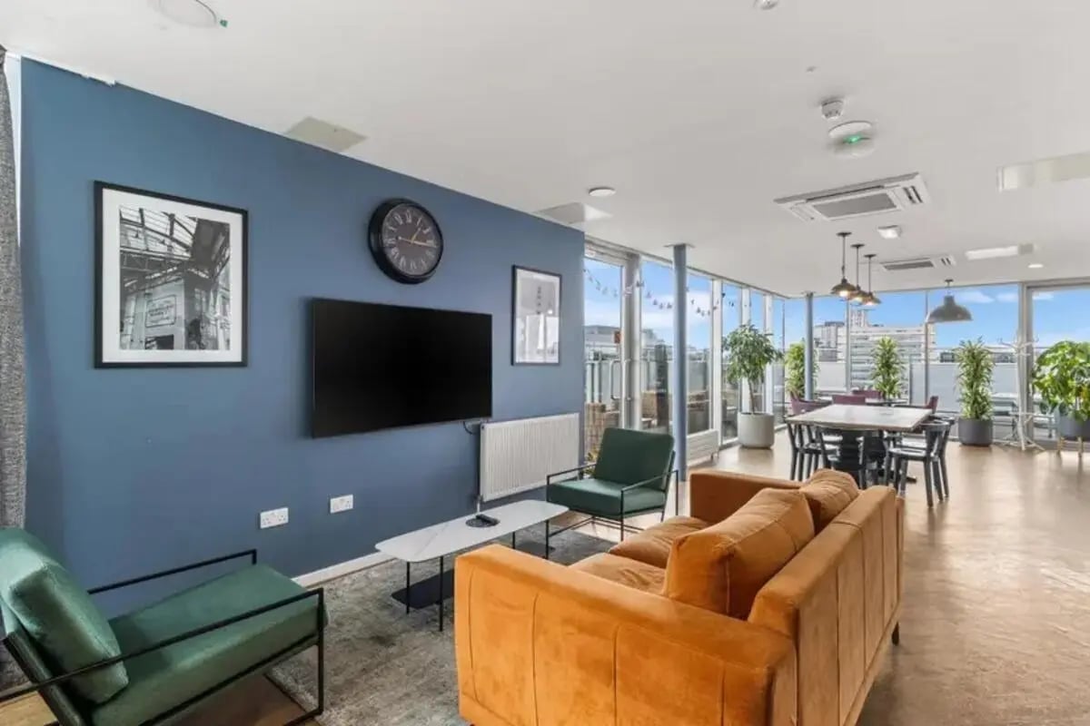 Sofa TV clock framed art chairs dining table plants communal area at Chapter South Bank in London Student Accommodation