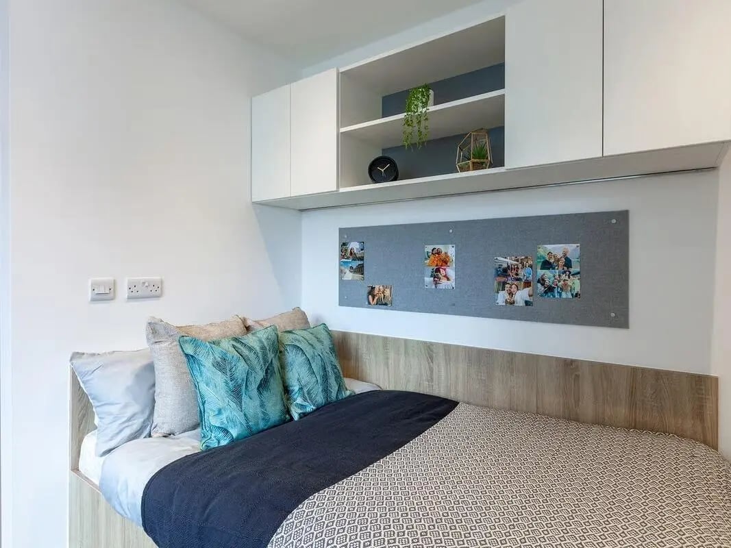 Bed pillows and photos on corkboard Bedroom at Saltwater Place in Plymouth Student Accommodation