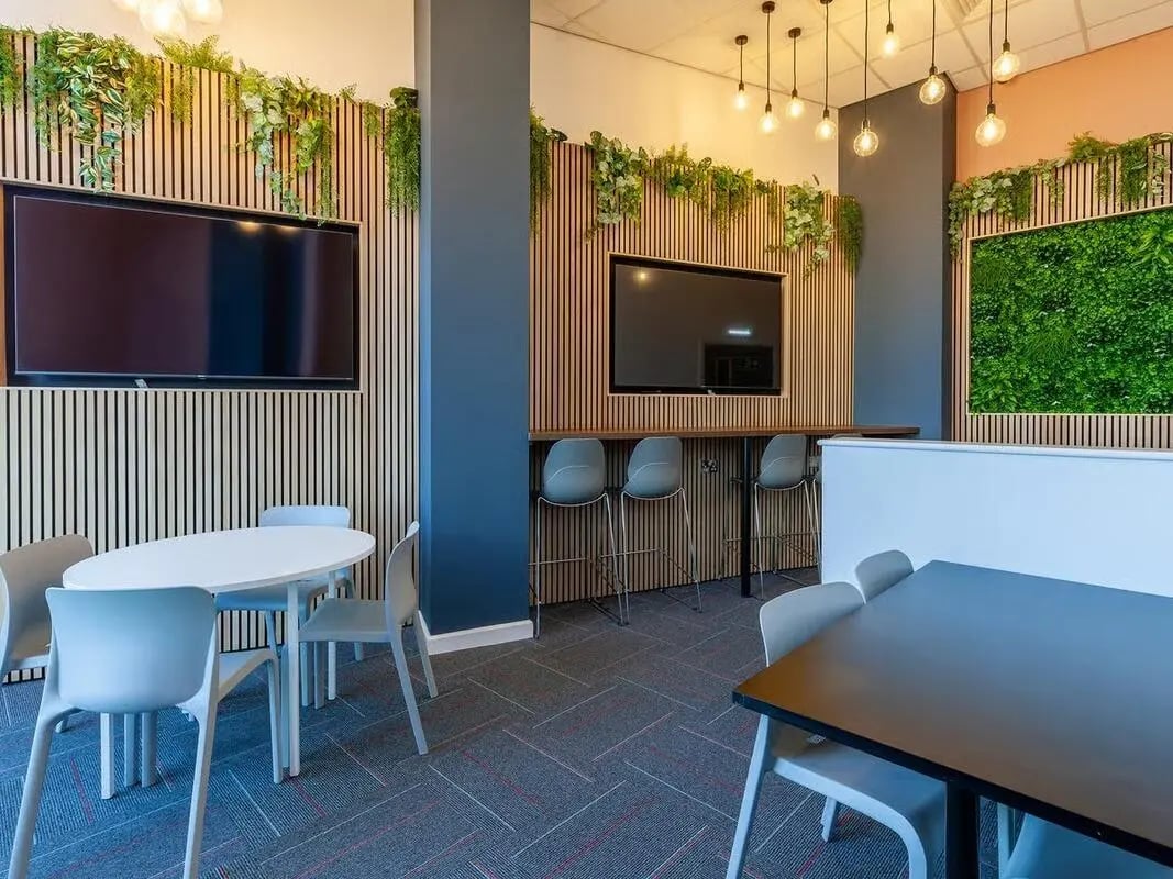 Two TVs tables chairs and plants lounge at Saltwater Place in Plymouth Student Accommodation