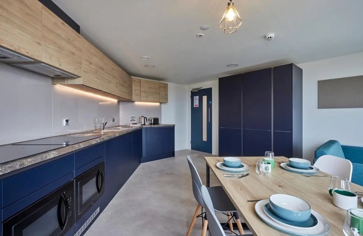 Blue cabinets microwaves and dining table kitchen at Regatta Place in Durham Student Accommodation