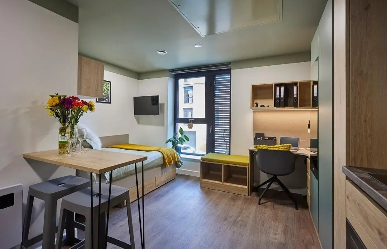 Bed desk with laptop and stools living room at Regatta Place in Durham Student Accommodation