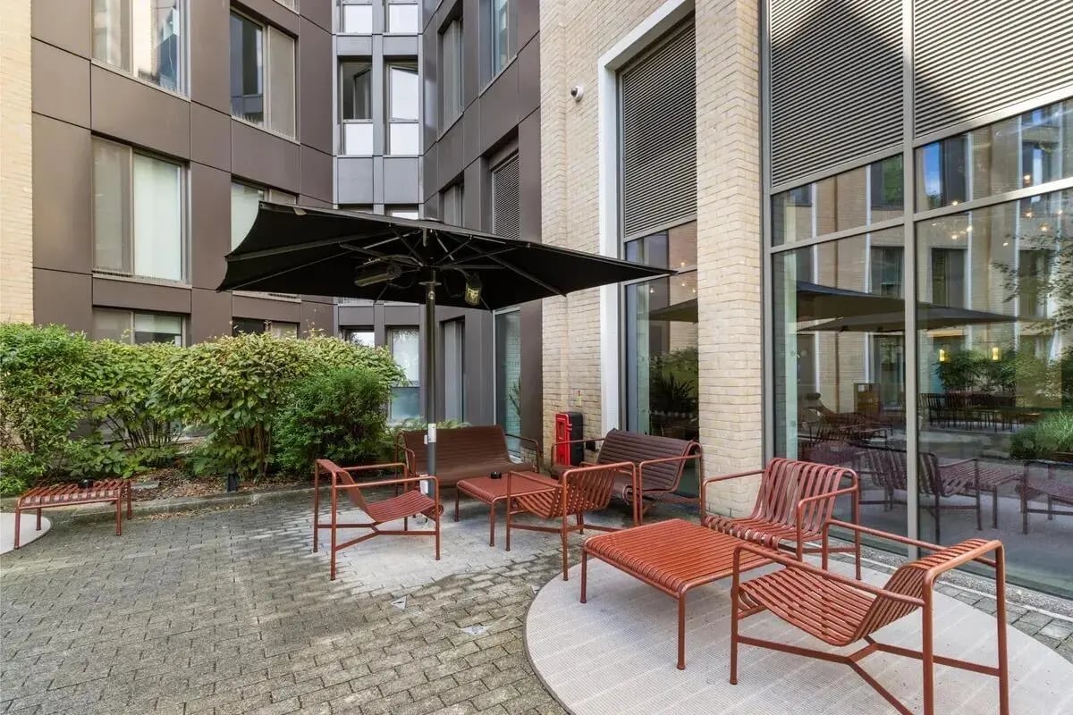 Outdoor seating with umbrella and greenery exterior at Chapter White City in London Student Accommodation