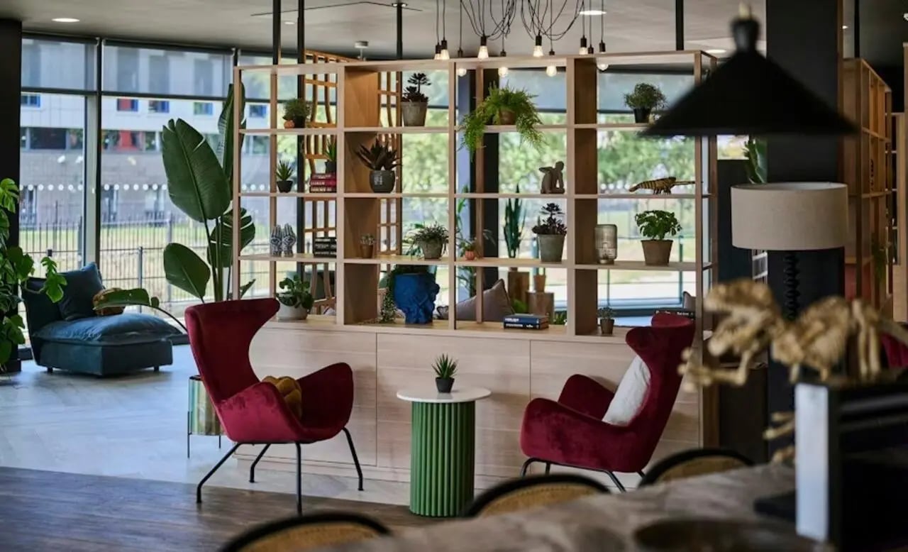 Two red chairs shelf plants and sofa living room at Deakins Place in Nottingham Student Accommodation