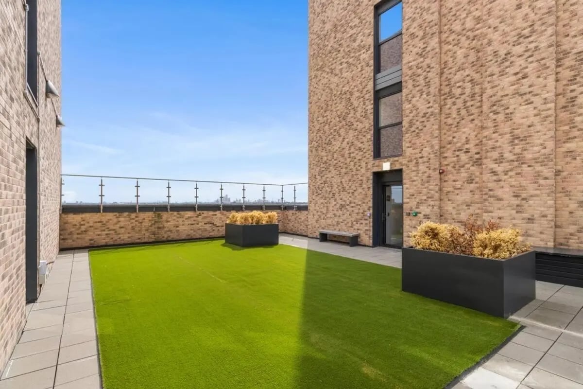 Artificial turf patio with planters and bench exterior at Canvas Walthamstow in London Student Accommodation