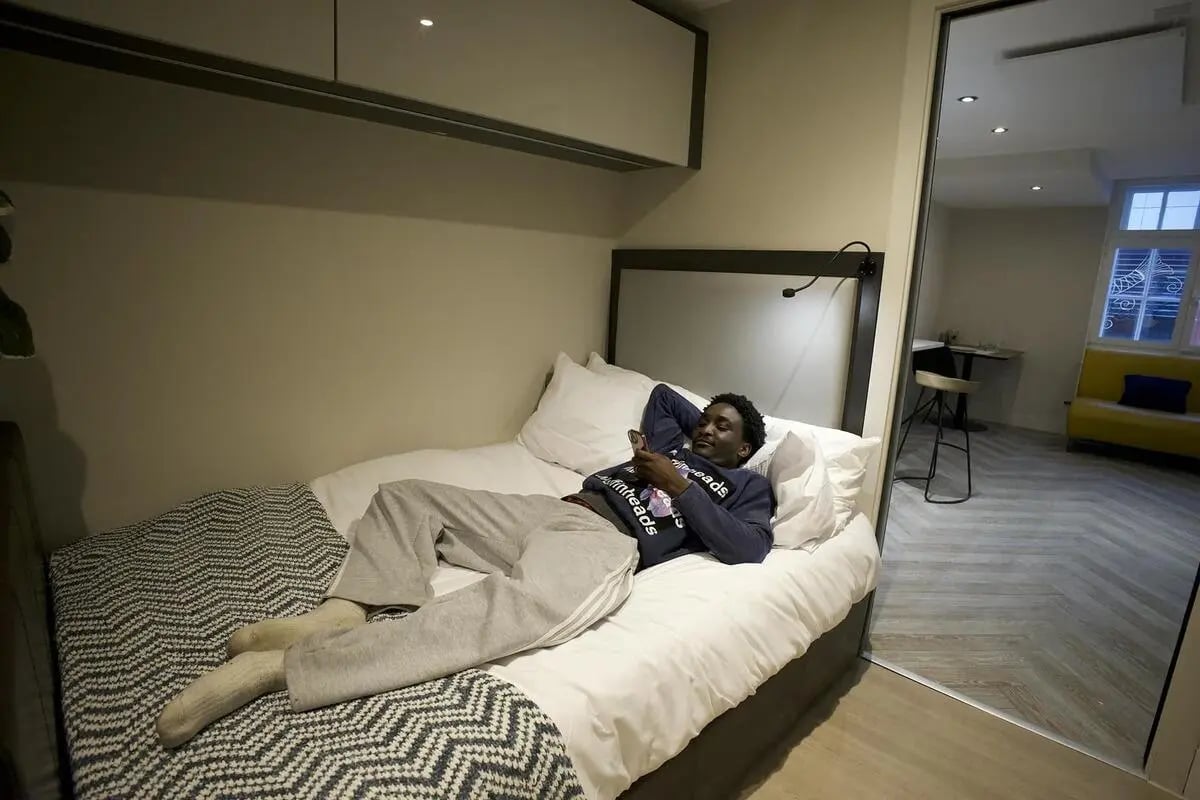 Man on bed with phone bedroom living room at dwell 121 Princess Street in Manchester Student Accommodation