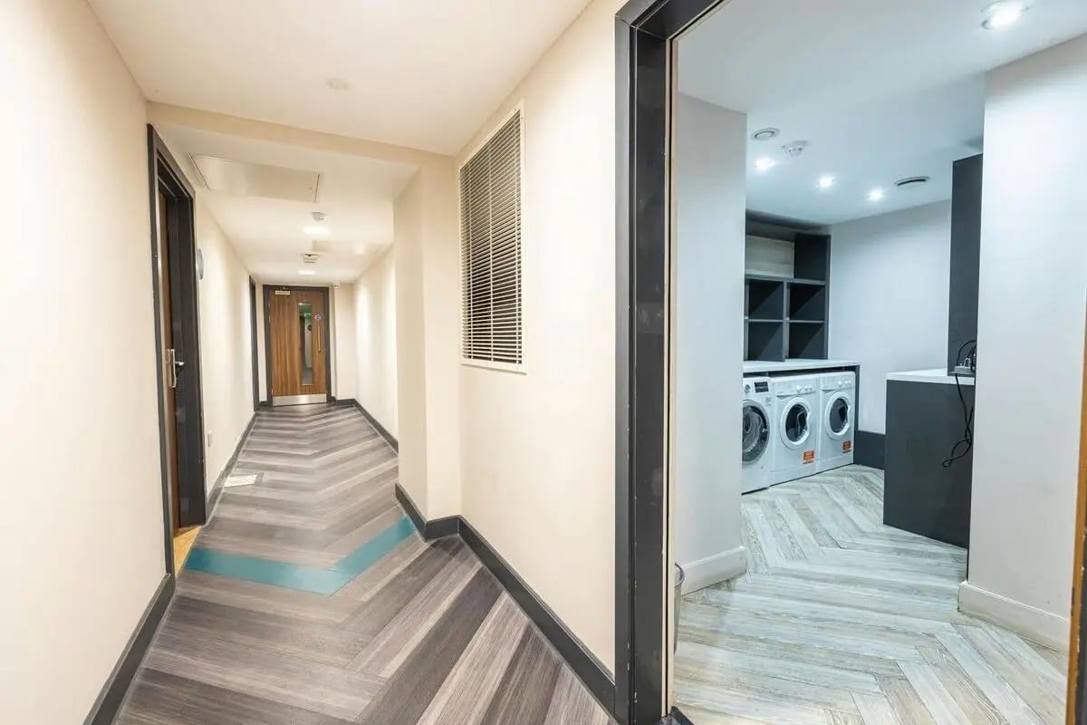Hallway with chevron flooring and laundry room laundry room at dwell 121 Princess Street in Manchester Student Accommodation