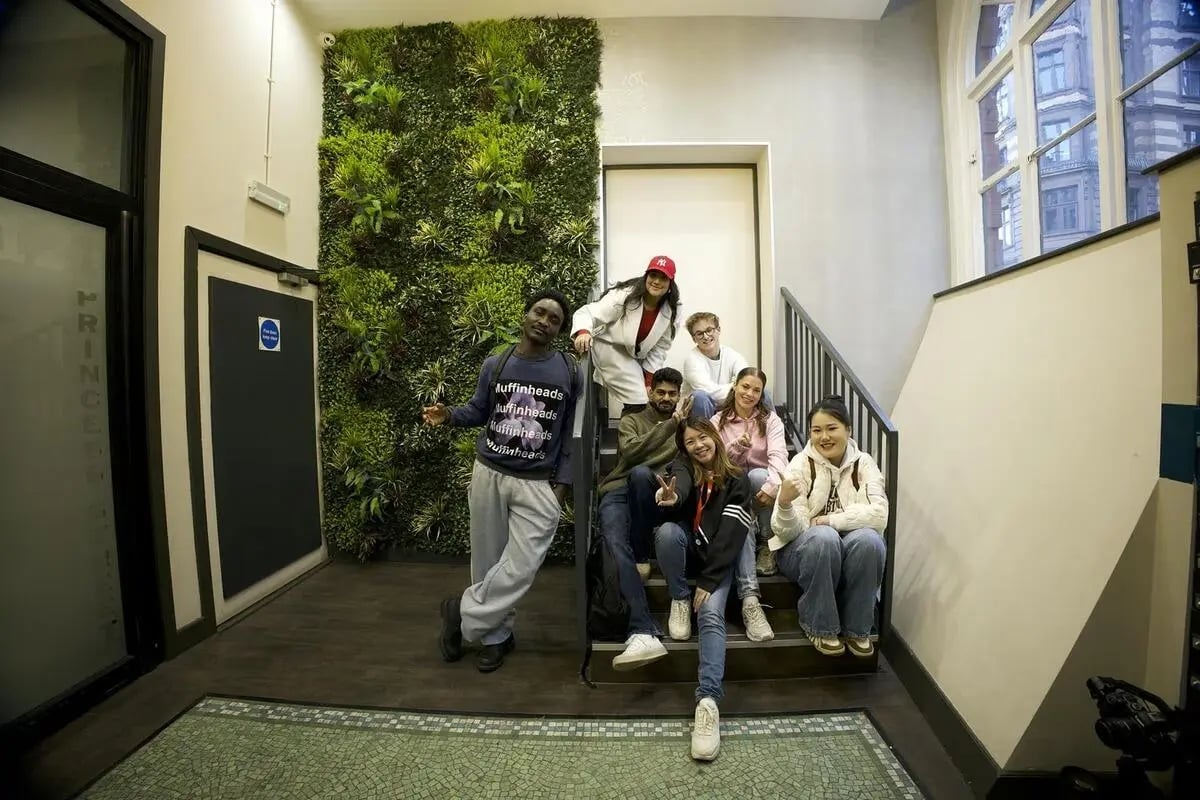 Students on stairs with green wall communal area at dwell 121 Princess Street in Manchester Student Accommodation