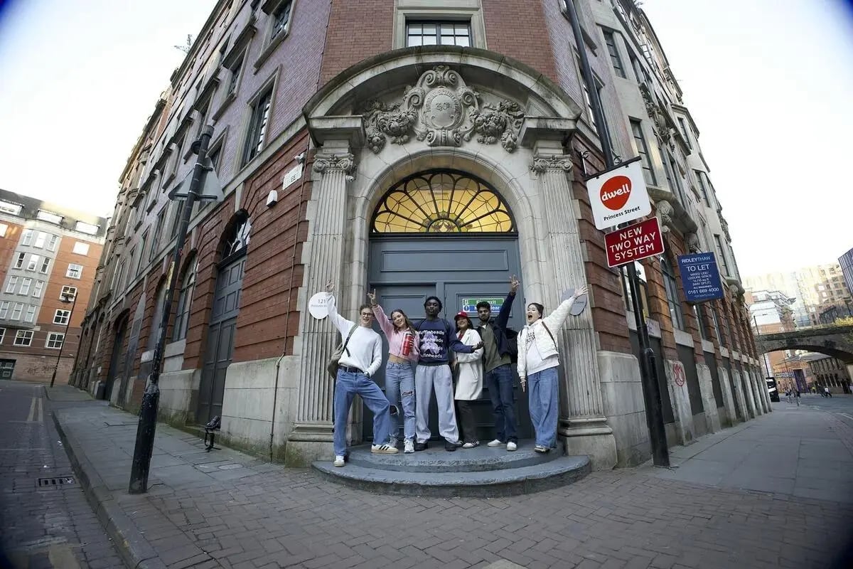 Students posing outside brick building exterior at dwell 121 Princess Street in Manchester Student Accommodation