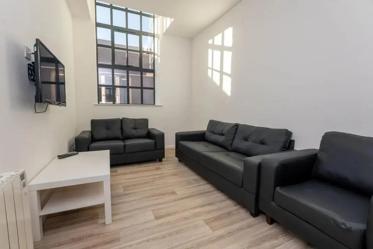 Black sofas white table large window living room at Bertrand Russell House in Nottingham Student Accommodation
