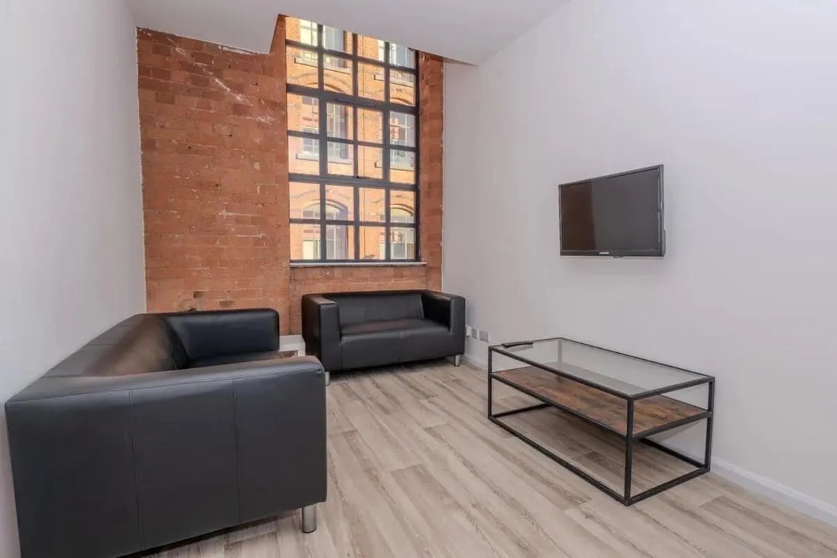 Two black sofas glass coffee table TV living room at Bertrand Russell House in Nottingham Student Accommodation